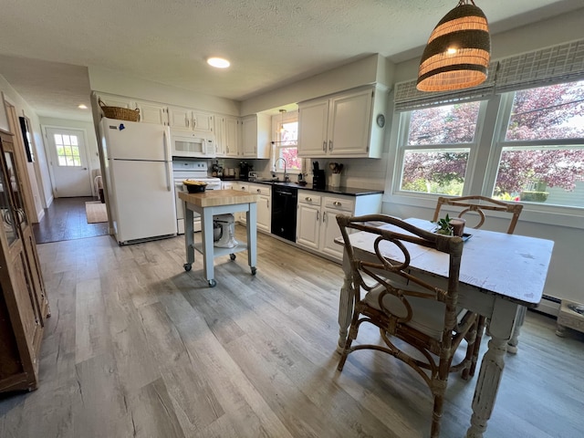 kitchen with white appliances, plenty of natural light, light wood finished floors, dark countertops, and a textured ceiling
