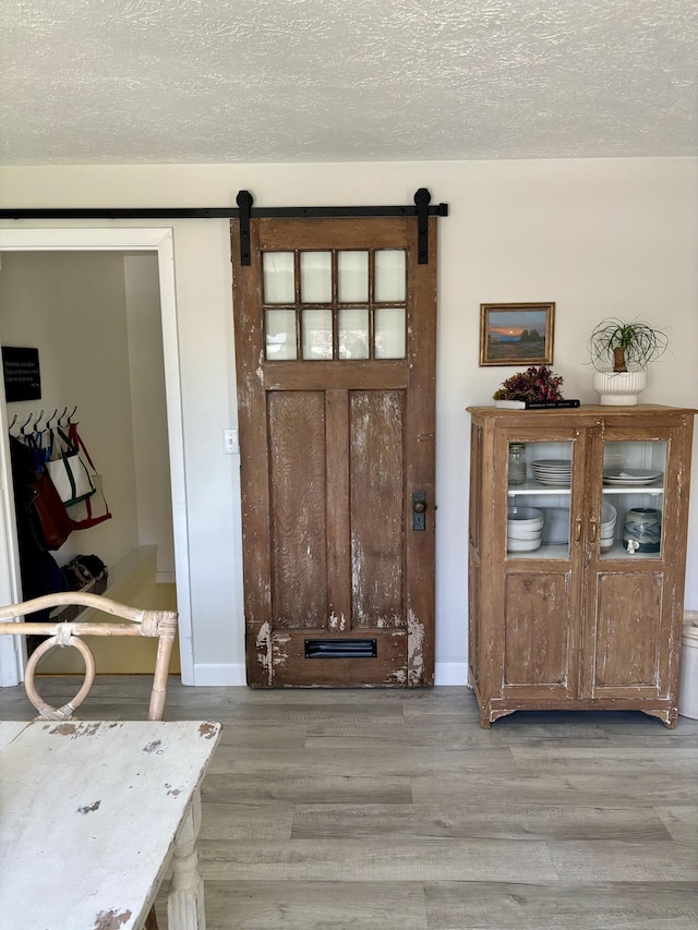 entryway featuring a barn door, light wood-style floors, a textured ceiling, and baseboards
