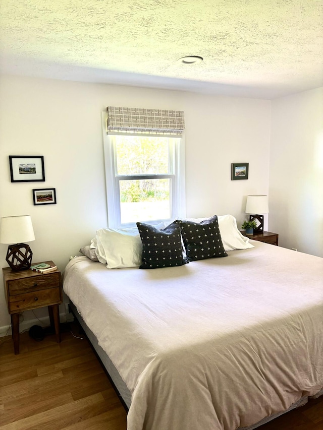 bedroom with wood finished floors and a textured ceiling