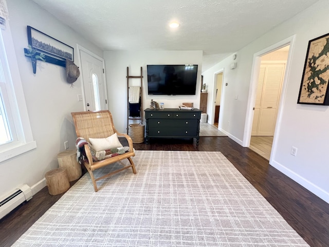 sitting room with dark wood-type flooring, baseboard heating, and baseboards