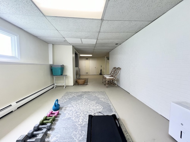exercise area featuring a baseboard heating unit and a paneled ceiling