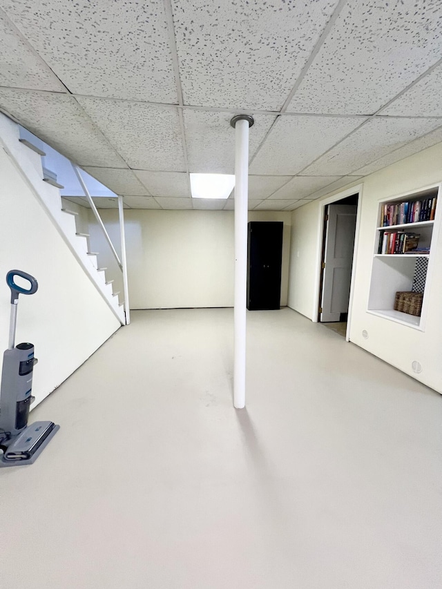 finished below grade area with a paneled ceiling and stairs