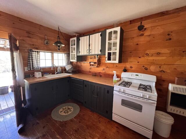 kitchen featuring white range with gas stovetop, a sink, heating unit, wood walls, and dark wood-type flooring