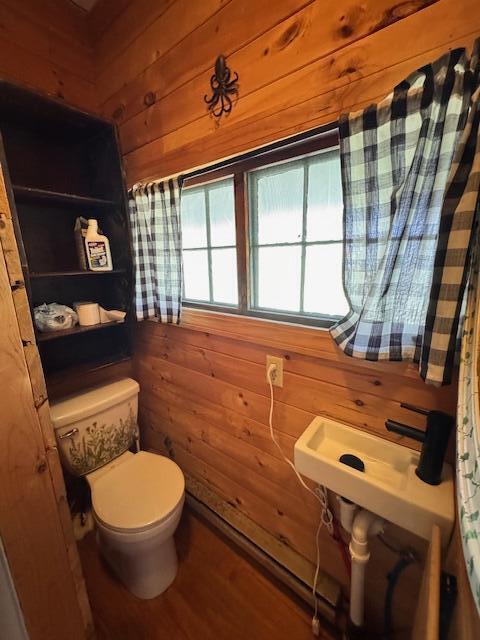 bathroom featuring wood walls, toilet, and wood finished floors