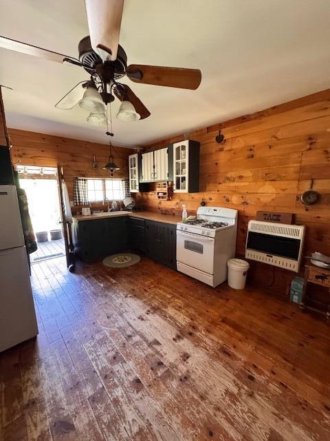 kitchen featuring white range with gas cooktop, heating unit, dark wood-type flooring, a peninsula, and glass insert cabinets
