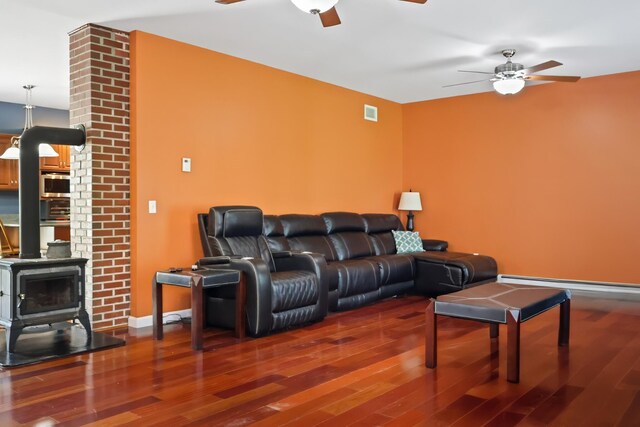 585 Charleston Rd, Charleston, ME 04422 - living room featuring a ceiling fan, a wood stove, wood finished floors, and a baseboard heating unit