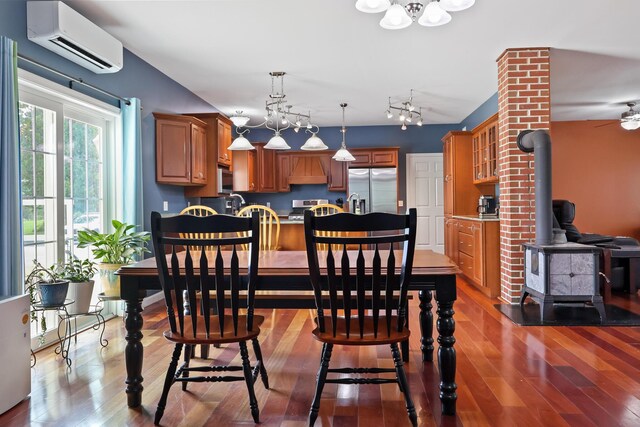 585 Charleston Rd, Charleston, ME 04422 - dining room with a wood stove, a wall unit AC, wood finished floors, and a chandelier