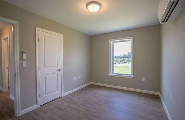 26 Stearns Farm Rd, Hampden, ME 04444 - spare room with an AC wall unit, wood finished floors, and baseboards