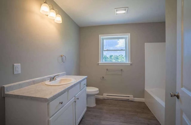 26 Stearns Farm Rd, Hampden, ME 04444 - full bath featuring a baseboard heating unit, toilet, vanity, baseboards, and wood finished floors