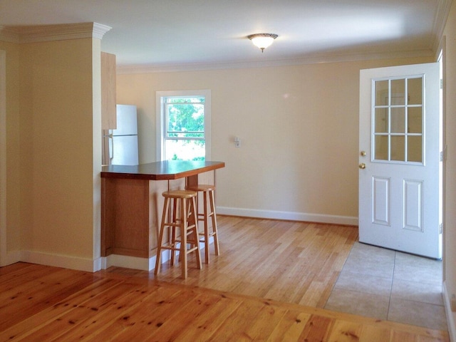 41 Church St, Damariscotta, ME 04543 - kitchen with freestanding refrigerator, crown molding, a kitchen bar, light wood-style flooring, and baseboards