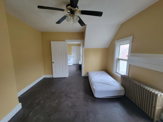 unfurnished bedroom featuring radiator heating unit, baseboards, lofted ceiling, a ceiling fan, and wood finished floors