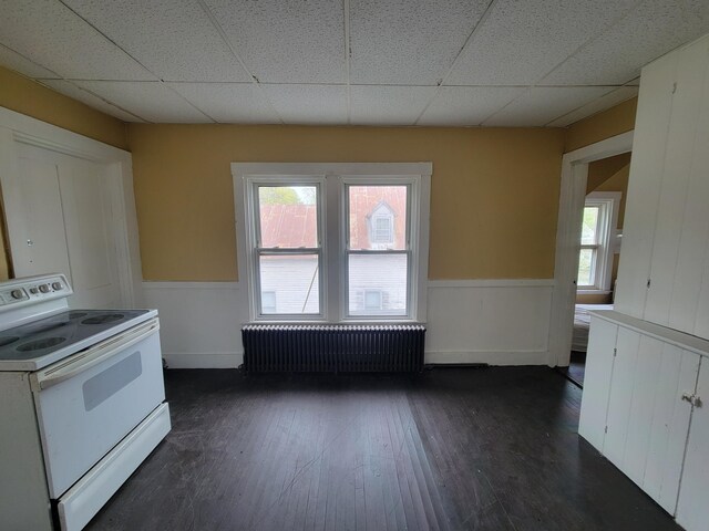 kitchen with electric range, radiator, wainscoting, dark wood-style flooring, and a paneled ceiling