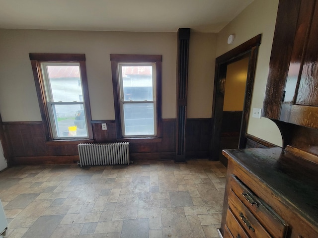 entrance foyer with radiator heating unit, stone tile flooring, and wainscoting