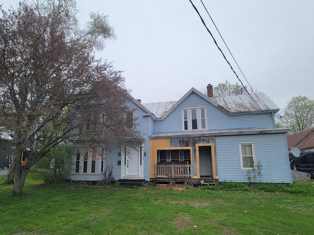 view of front of house with metal roof, a front lawn, covered porch, and a chimney