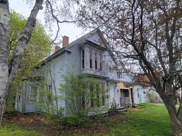 view of property exterior featuring a chimney and a lawn