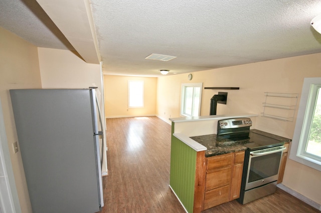 26 Flat Iron Rd, Tremont, ME 04653 - kitchen with appliances with stainless steel finishes, open floor plan, a textured ceiling, dark wood-style flooring, and a wood stove