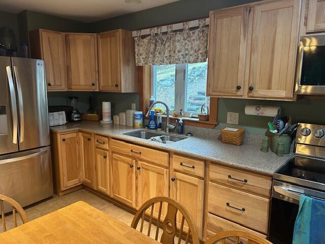 119 Sunset Dr, Sebec, ME 04481 - kitchen featuring stainless steel appliances, a sink, light tile patterned floors, light countertops, and light brown cabinets