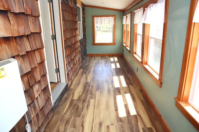 hall with wood finished floors, crown molding, and baseboards