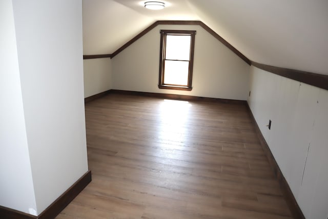 bonus room featuring lofted ceiling, light wood-style floors, and baseboards