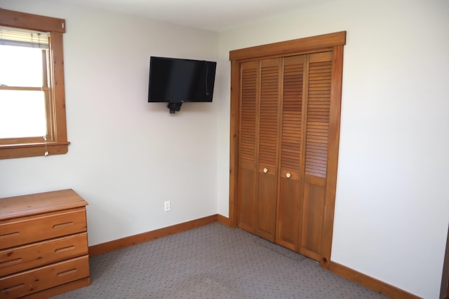 unfurnished bedroom with baseboards, a closet, and light carpet