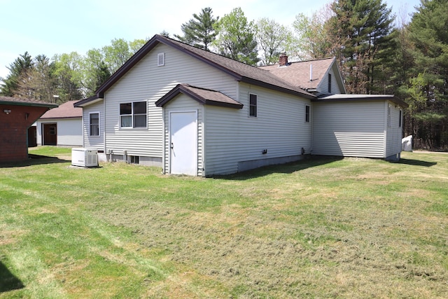 back of property featuring a yard, a chimney, and roof with shingles
