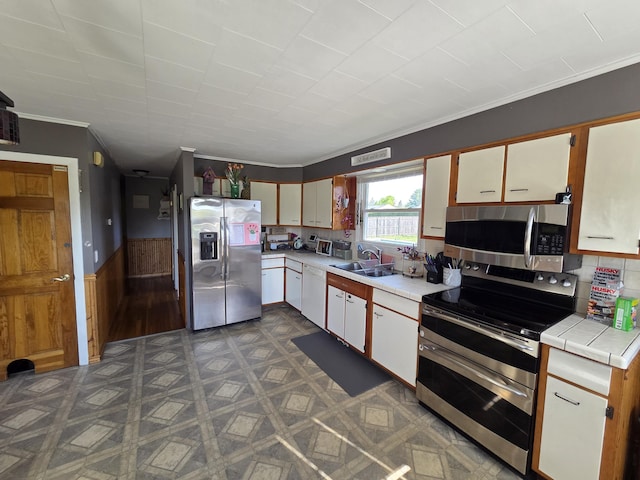 36 Lorraine Ave, Brewer, ME 04412 - kitchen with appliances with stainless steel finishes, a sink, ornamental molding, tile counters, and wainscoting