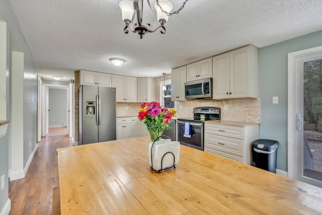kitchen featuring appliances with stainless steel finishes, wood counters, tasteful backsplash, a textured ceiling, and wood finished floors