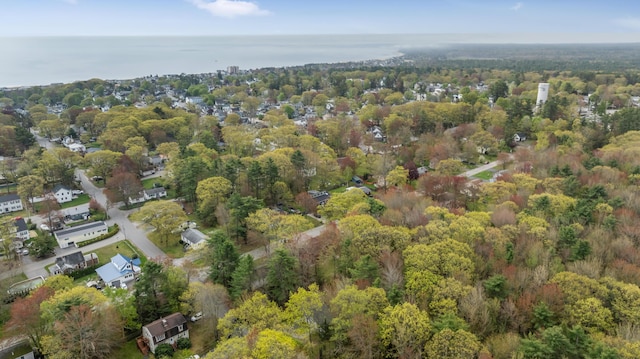 aerial view of property and surrounding area with a heavily wooded area and a nearby body of water
