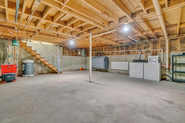 unfinished basement featuring oil tank, electric water heater, washer and dryer, and stairway