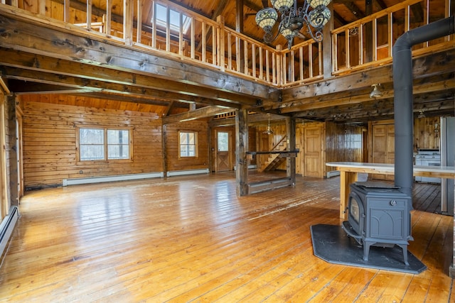 526 Range Rd, Dover-Foxcroft, ME 04426 - unfurnished living room with a wood stove, wood walls, wood-type flooring, baseboard heating, and a chandelier