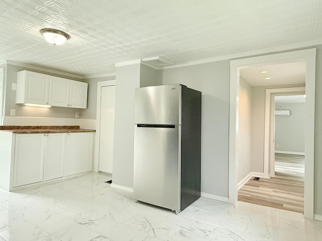 46 French St, Skowhegan, ME 04976 - kitchen with freestanding refrigerator, dark countertops, light marble finish floors, ornamental molding, and white cabinets