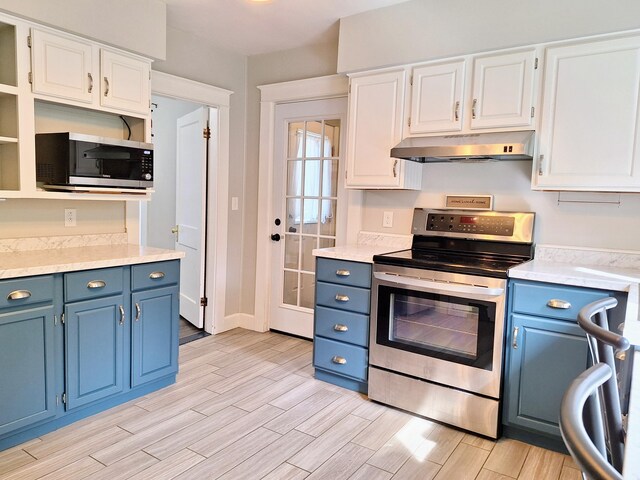 kitchen with appliances with stainless steel finishes, under cabinet range hood, blue cabinets, open shelves, and light wood-style flooring