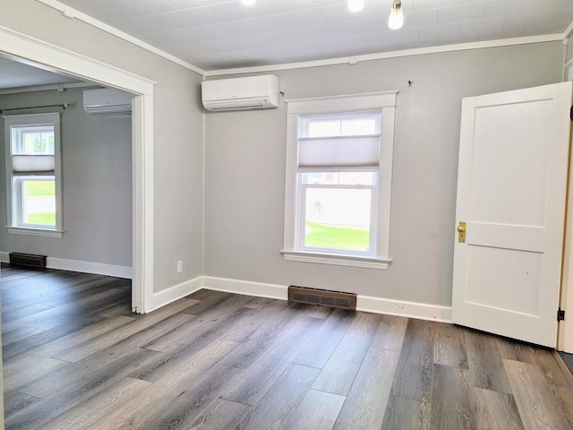 unfurnished room with a wall unit AC, ornamental molding, dark wood-type flooring, and baseboards