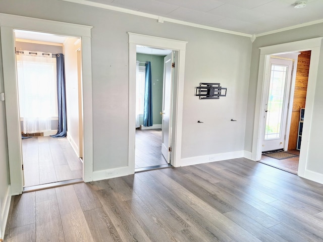 empty room featuring ornamental molding, wood finished floors, and baseboards