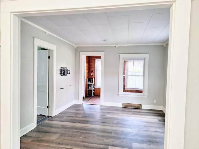 empty room with ornamental molding, dark wood-type flooring, and baseboards