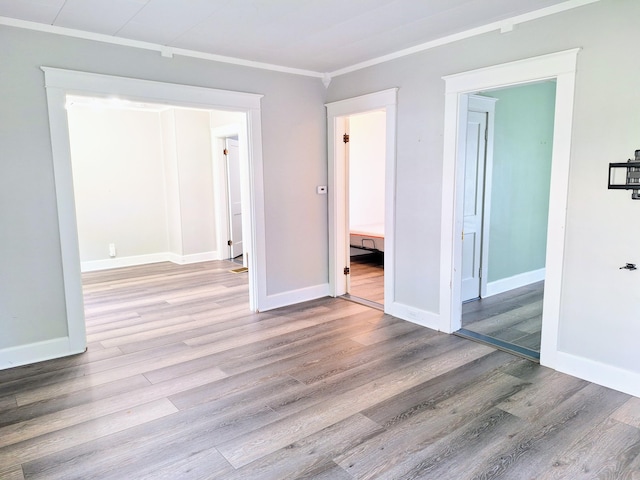 spare room featuring wood finished floors, baseboards, and crown molding