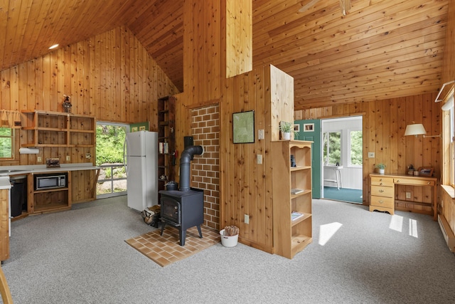 67 Day Mountain Rd, Temple, ME 04984 - living room with wood walls, carpet flooring, wooden ceiling, a wood stove, and baseboard heating