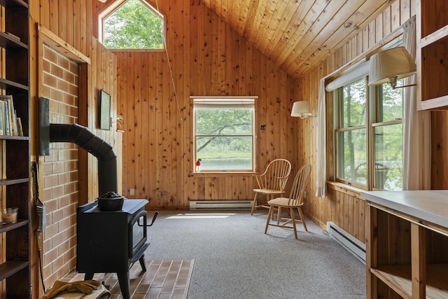 67 Day Mountain Rd, Temple, ME 04984 - living area with a wood stove, a baseboard heating unit, vaulted ceiling, plenty of natural light, and wood walls
