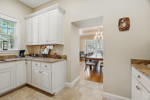 1026 Essex St, Bangor, ME 04401 - kitchen featuring a chandelier, plenty of natural light, white cabinets, and baseboards