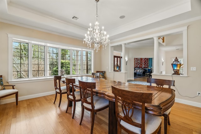 1026 Essex St, Bangor, ME 04401 - dining room featuring ornate columns, a raised ceiling, light wood-type flooring, baseboards, and crown molding
