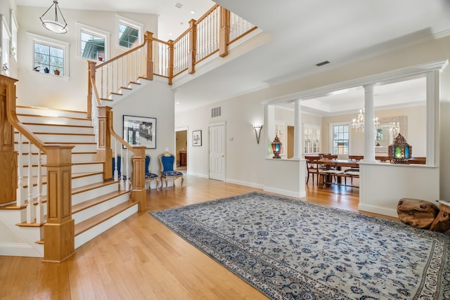1026 Essex St, Bangor, ME 04401 - foyer entrance featuring wood finished floors, ornate columns, stairs, crown molding, and a high ceiling