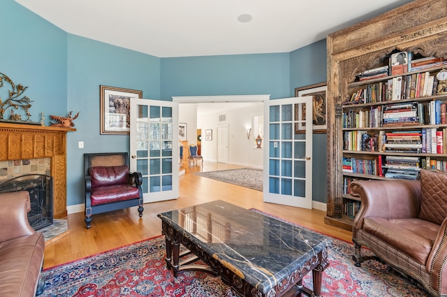 1026 Essex St, Bangor, ME 04401 - living area featuring french doors, wood finished floors, a tile fireplace, and baseboards