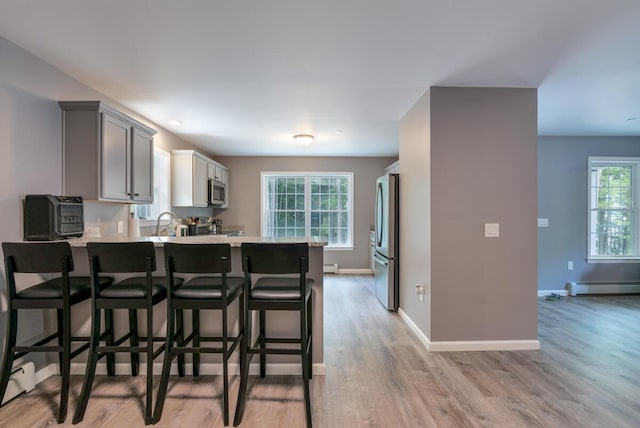 313 Nevells Way, Ellsworth, ME 04605 - kitchen featuring appliances with stainless steel finishes, a baseboard heating unit, light wood-type flooring, a peninsula, and a breakfast bar area
