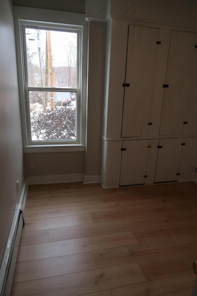 11 Green St, Winthrop, ME 04364 - unfurnished bedroom with baseboard heating, light wood finished floors, baseboards, and a closet