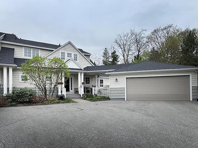 view of front of home featuring a garage, covered porch, and asphalt driveway