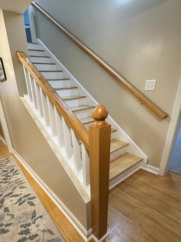 staircase featuring wood finished floors and baseboards