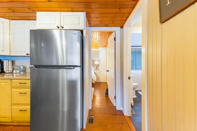 61 Beechwoods Rd, Oxford, ME 04270 - kitchen with freestanding refrigerator, wood finished floors, wood ceiling, white cabinetry, and light stone counters