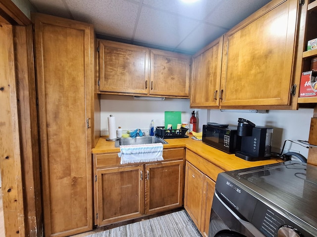 58 Back Shore Rd, Castine, ME 04421 - kitchen with light countertops, black microwave, washer / dryer, brown cabinets, and a drop ceiling