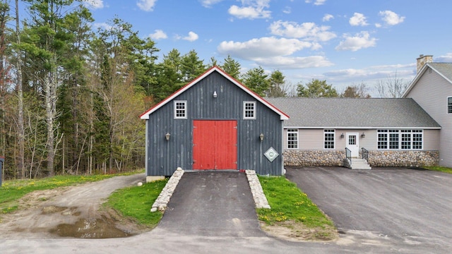 20 Motorcycle Dr, Windham, ME 04062 - view of front of property with a shingled roof, stone siding, asphalt driveway, and an outbuilding