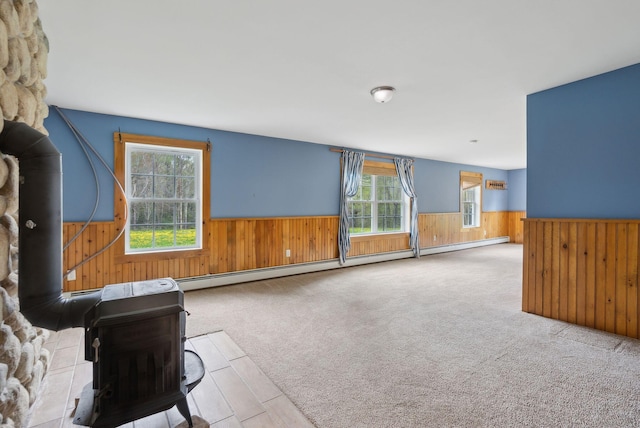 20 Motorcycle Dr, Windham, ME 04062 - unfurnished living room with wainscoting, wood walls, plenty of natural light, a wood stove, and a baseboard heating unit